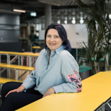 Galina Charni sitting at a yellow table smiling at the camera