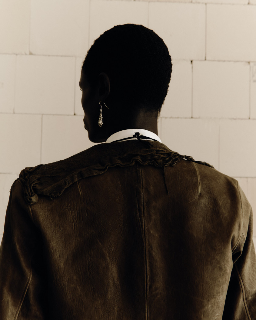 A Black model seen from behind; a large silver earring in stark visual contrast to their dark skin