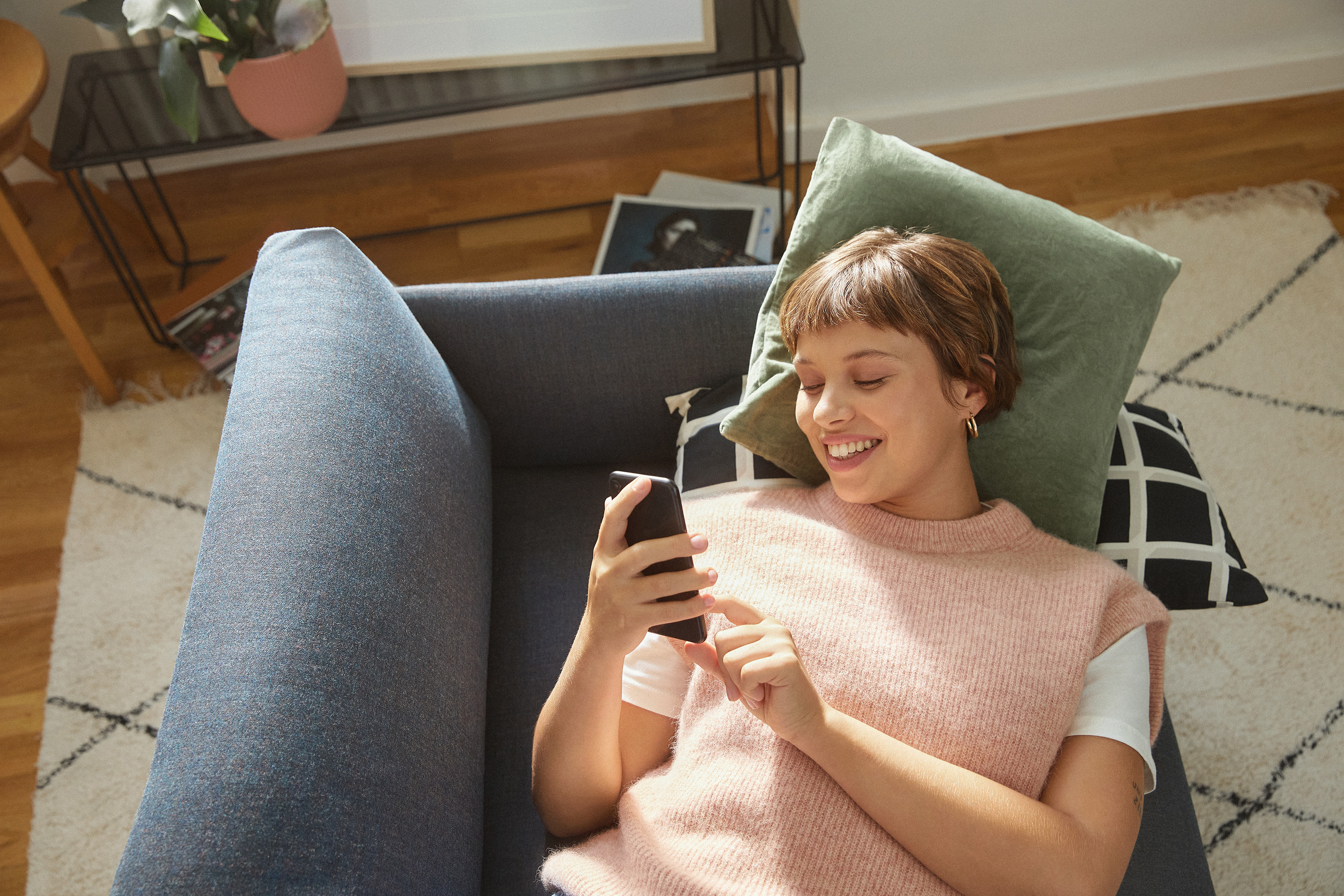 Customer enjoying Zalando Female customer lying on a sofa, smiling at her phone