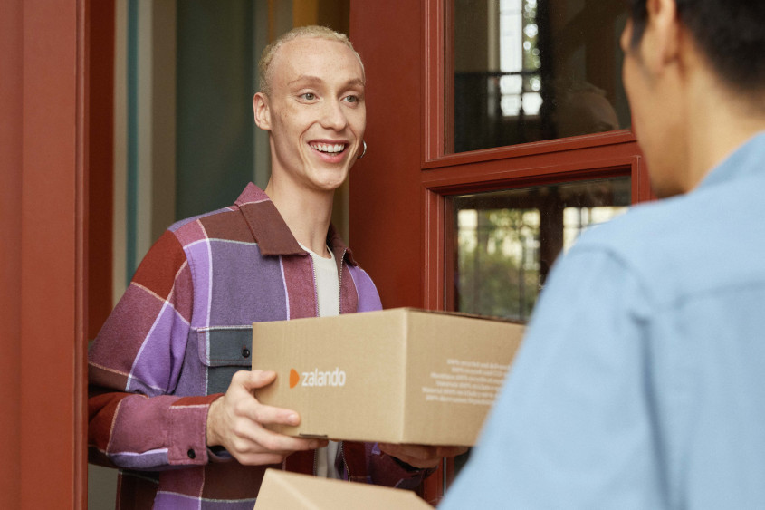 Zalando SE customer receives delivery A person receives a Zalando package from a messenger at the front door.